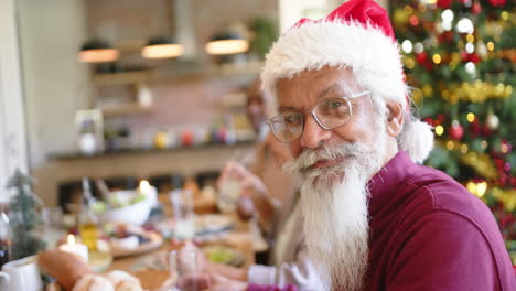 Happy-biracial-man-with-beard-and-hat-at-christmas-dinner-table-with-diverse-friends,-slow-motion