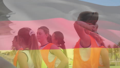 Animation-of-germany-and-european-flag-over-diverse-coach-discussing-with-female-players
