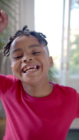 Vertical-video-portrait-of-happy-african-american-boy-with-dreadlocks-smiling,-slow-motion