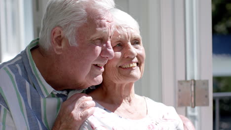 Happy-senior-caucasian-couple-standing-on-balcony-and-embracing,-slow-motion