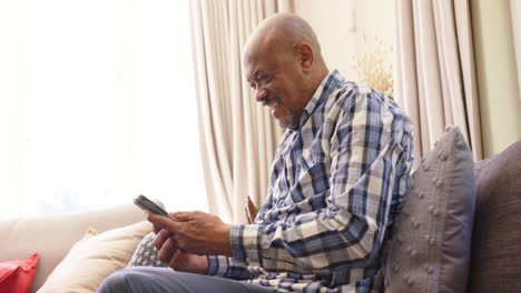 Überrascht,-Dass-Ein-älterer-Afroamerikanischer-Mann-In-Einem-Sonnigen-Zimmer-Einen-Smartphone-Anruf-Entgegennimmt,-Platz-Zum-Kopieren,-Zeitlupe