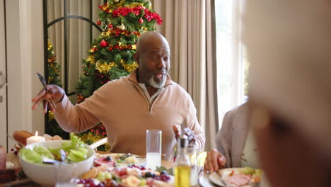 Happy-diverse-senior-couple-embracing-at-christmas-dinner-table-with-friends,-slow-motion
