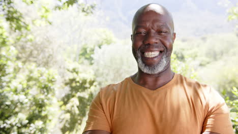 Portrait-of-happy-bald-senior-african-american-man-smiling-in-sunny-nature,-copy-space,-slow-motion
