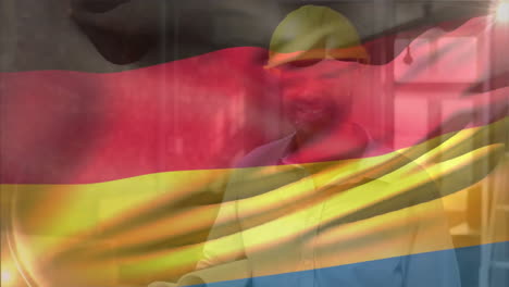 Animation-of-german-flag-waving,-biracial-engineer-wearing-helmet-walking-with-blueprints