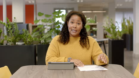 Portrait-of-casual-biracial-businesswoman-on-video-call-in-office,-slow-motion-with-copy-space