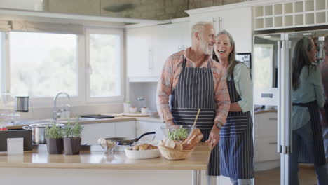 Middle-aged-caucasian-couple-putting-apron,-cooking-in-kitchen-at-home,-slow-motion