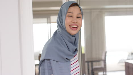 Portrait-of-smiling-biracial-woman-in-hijab-at-home-with-copy-space,-slow-motion
