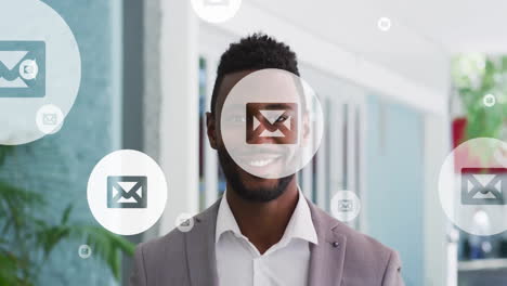 Animation-of-envelope-icon-in-circles-over-smiling-african-american-man-standing-in-office