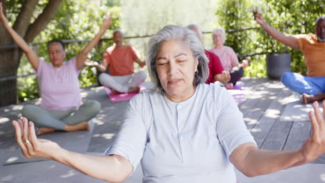 Feliz-Y-Diversa-Instructora-Senior-Y-Amigos-Practicando-Meditación-De-Yoga-Al-Sol,-Cámara-Lenta