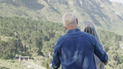 Happy-middle-aged-caucasian-couple-embracing-and-talking-on-terrace-in-mountains,-slow-motion