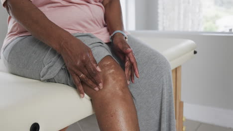 Ältere-Afroamerikanische-Frau-Berührt-Ihr-Knie,-Kopierraum,-Zeitlupe