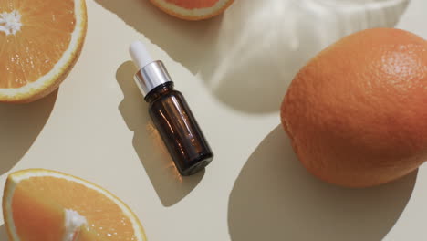 Video-of-make-up-bottle-with-pipette,-citrus-slices-and-copy-space-on-yellow-background