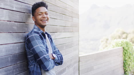 Retrato-De-Un-Hombre-Afroamericano-Feliz-Parado-En-Un-Balcón-Soleado-Sonriendo,-Espacio-Para-Copiar,-Cámara-Lenta