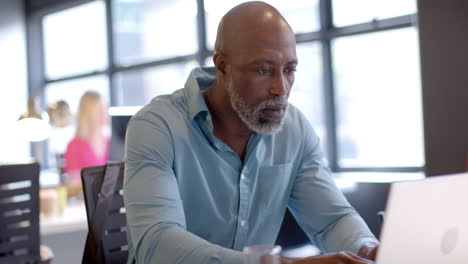African-american-businessman-using-laptop-in-office-with-copy-space