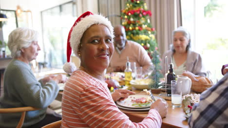 Feliz-Anciana-Afroamericana-En-La-Mesa-De-La-Cena-De-Navidad-Con-Diversos-Amigos,-Cámara-Lenta