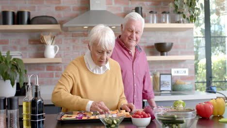 Happy-senior-caucasian-couple-cooking-dinner-in-kitchen-at-home,-slow-motion