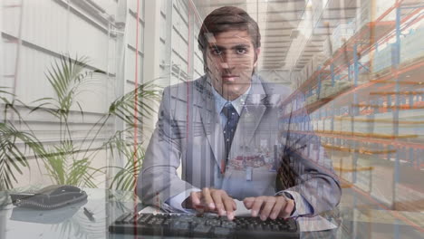 Animation-of-aerial-view-of-warehouse-over-caucasian-businessman-typing-on-keyboard-at-office