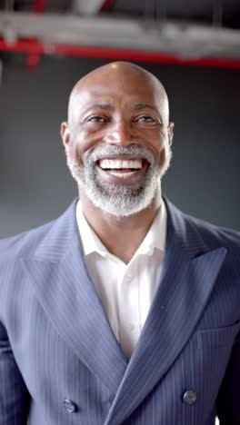 Vertical-video-of-smiling-african-american-businessman-in-office-with-copy-space