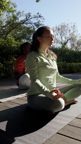 Vertikales-Video-Eines-Vielfältigen-Paares,-Das-Yoga-Meditation-Praktiziert-Und-In-Der-Sonne-Sitzt,-Zeitlupe