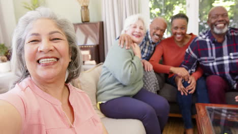 Happy-senior-caucasian-woman-taking-selfie-with-diverse-friends-in-sunny-room,-slow-motion