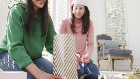 Glückliche-Biracial-Mutter-Und-Erwachsene-Tochter-Verpacken-Weihnachtsgeschenk-Zu-Hause,-Kopierraum,-Zeitlupe