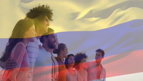Animation-of-flag-of-colombia-waving-over-diverse-friends-forming-human-chain-and-looking-at-sea