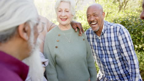 Happy-diverse-senior-female-and-male-friends-embracing-and-laughing-in-sunny-garden,-slow-motion