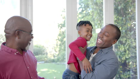 Portrait-of-happy-african-american-father,-son-and-grandfather-embracing-in-sunny-room,-slow-motion