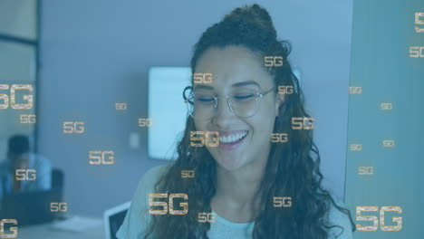 Animation-of-multiple-5g-texts-over-close-up-of-smiling-biracial-woman-in-office