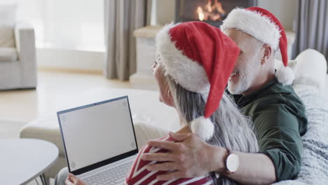 Middle-aged-caucasian-couple-with-laptop-with-blank-screen-at-christmas-at-home,-slow-motion