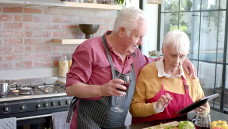 Senior-caucasian-couple-cooking-dinner-using-tablet-in-kitchen-at-home,-slow-motion