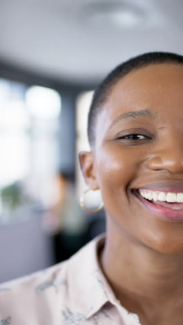 Vertical-video-of-smiling-african-american-businesswoman-in-office,-slow-motion,-copy-space