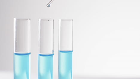 Video-of-glass-laboratory-test-tubes-and-pipette-with-blue-liquid-and-copy-space-on-white-background