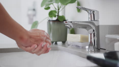 Close-up-of-biracial-woman-washing-hands-in-bathroom,-slow-motion