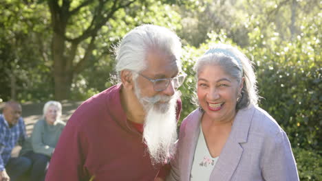 Portrait-of-happy-diverse-senior-couple-embracing-in-sunny-garden-with-friends,-slow-motion
