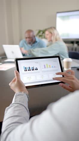 Vertical-video-of-afrcian-american-businesswoman-using-tablet-with-copy-space-in-office