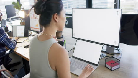 Asian-businesswoman-using-tablet-and-computer-with-blank-screen-in-office,-slow-motion,-copy-space