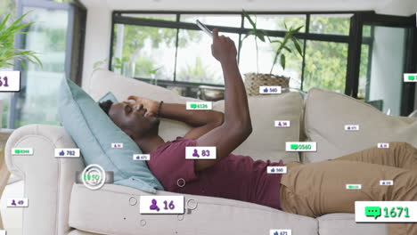 Animation-of-notification-bars-over-african-american-man-lying-on-sofa-and-scrolling-on-cellphone
