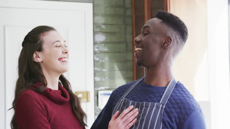 Happy-diverse-couple-standing-in-kitchen,-laughing-and-embracing,slow-motion