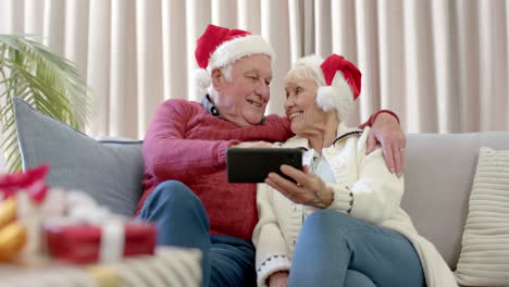 Älteres-Kaukasisches-Paar-Mit-Weihnachtsmützen,-Das-Sein-Smartphone-Für-Einen-Weihnachtsvideoanruf-In-Zeitlupe-Nutzt