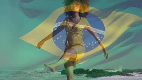 Animation-of-waving-flag-of-brazil-over-biracial-woman-walking-and-enjoying-breeze-at-beach