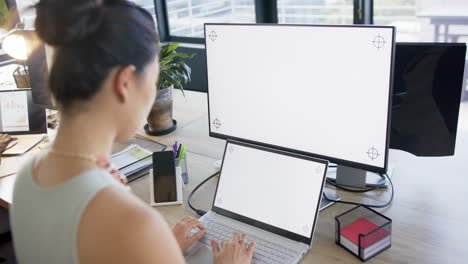 Asian-businesswoman-using-tablet-and-computer-with-blank-screen-in-office,-slow-motion,-copy-space
