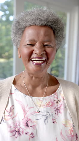 Vertical-video-portrait-of-happy-senior-african-american-woman-laughing-at-home,-slow-motion