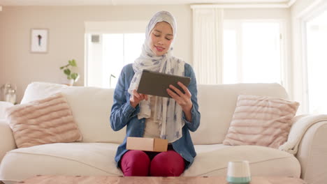 Glückliche-Biracial-Frau-Im-Hijab-Mit-Tablet-Auf-Dem-Sofa-Zu-Hause-Mit-Kopierplatz,-Zeitlupe