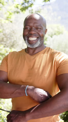 Vertical-video-portrait-of-happy-bald-senior-african-american-man-smiling-out-in-sun,-slow-motion