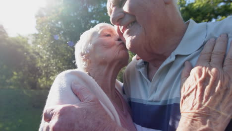 Glückliches-älteres-Kaukasisches-Paar,-Das-Sich-Im-Sonnigen-Garten-Umarmt-Und-Küsst,-Zeitlupe