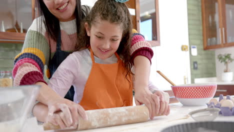 Glückliche-Biracial-Mutter-Und-Tochter-Rollen-Teig-Aus-Und-Lächeln-In-Sonniger-Küche