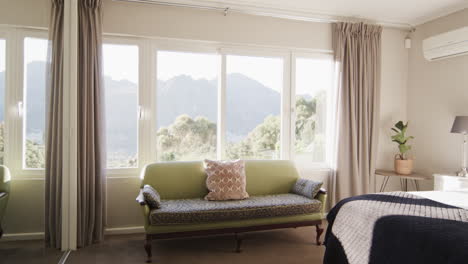 Panning-shot-of-sunny-bedroom-home-interior-with-views-to-mountainside,-slow-motion