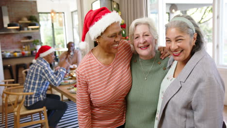 Happy-diverse-senior-female-friends-embracing-after-christmas-meal-with-friends,-slow-motion