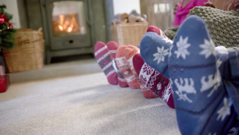 Feet-of-african-american-family-in-warm-socks-by-fireplace-in-living-room,-copy-space,-slow-motion